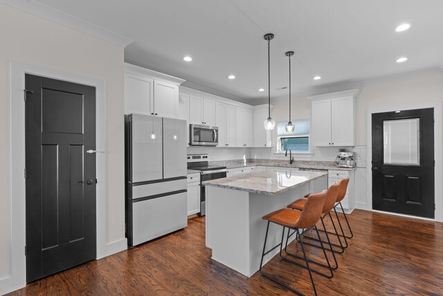 kitchen featuring dark wood-style flooring, white cabinetry, stainless steel appliances, and a kitchen island