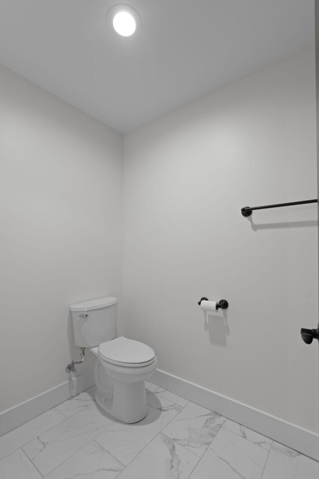 bathroom with marble finish floor, baseboards, and toilet