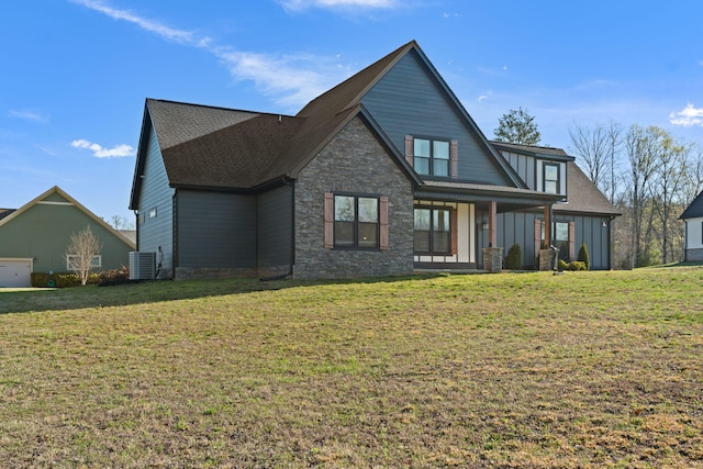 view of front of property with a front yard, cooling unit, stone siding, and a garage