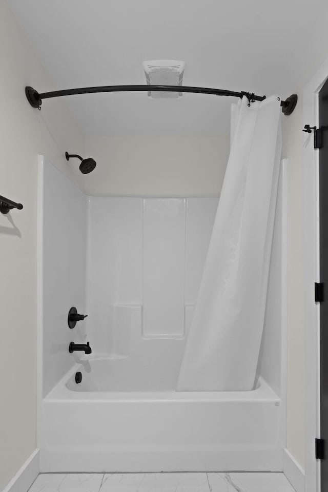 bathroom featuring baseboards, marble finish floor, and shower / bath combination with curtain