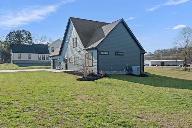 view of side of property with driveway, roof with shingles, an attached garage, a lawn, and central AC