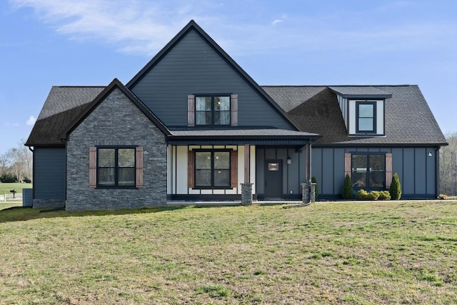 view of front of house with stone siding, board and batten siding, a front yard, covered porch, and a shingled roof