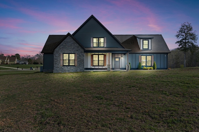 view of front of home with a porch, stone siding, board and batten siding, and a yard