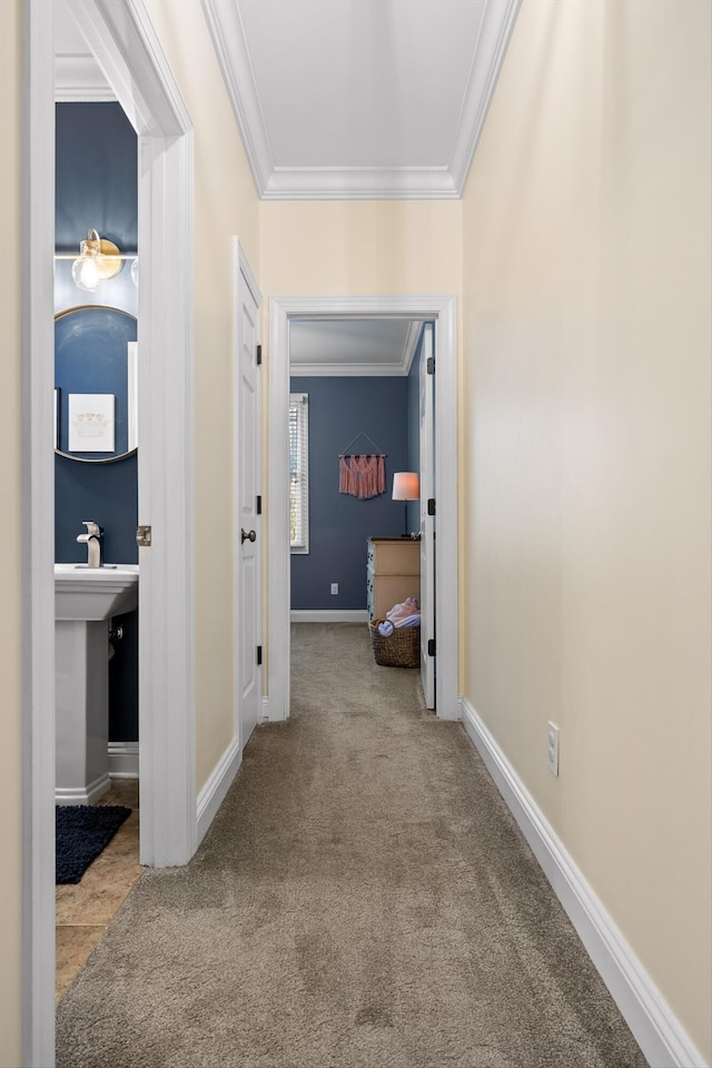 corridor with carpet flooring, a sink, crown molding, and baseboards