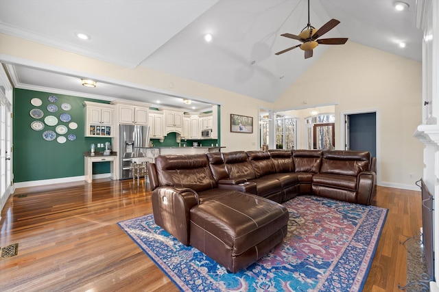 living area with crown molding, high vaulted ceiling, wood finished floors, baseboards, and ceiling fan