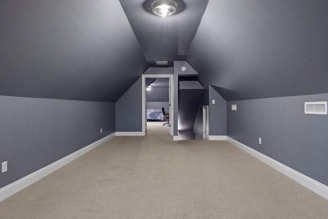additional living space with baseboards, visible vents, carpet floors, and vaulted ceiling