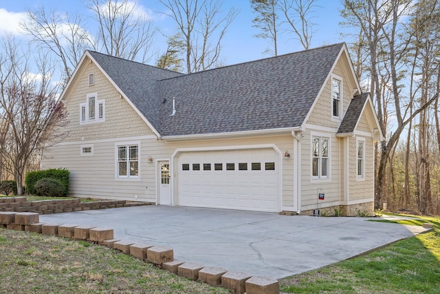 view of side of home featuring a shingled roof, an attached garage, and concrete driveway