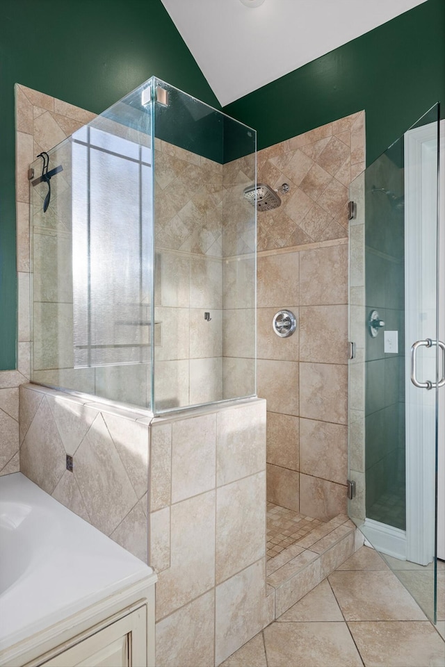 bathroom featuring tile patterned flooring, a stall shower, lofted ceiling, and a garden tub