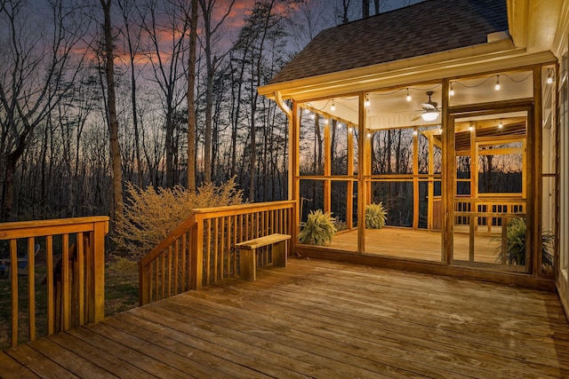 deck at dusk featuring a sunroom