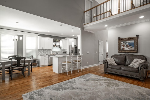8975 Silver Maple Dr, Ooltewah, TN 37363 - living area with ornamental molding, light wood-type flooring, a notable chandelier, and a towering ceiling