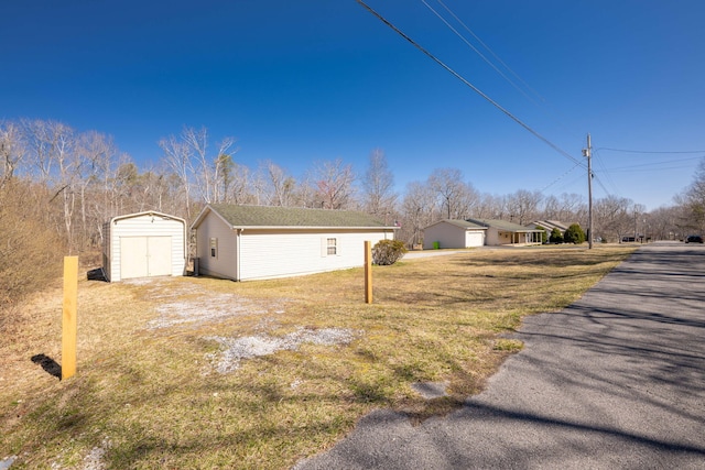 view of yard featuring a shed, a detached garage, and an outdoor structure