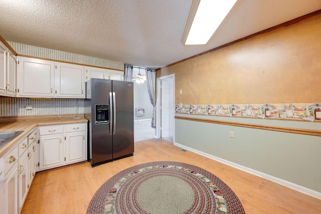 kitchen featuring white cabinetry, light wood-style floors, stainless steel fridge, and a textured ceiling