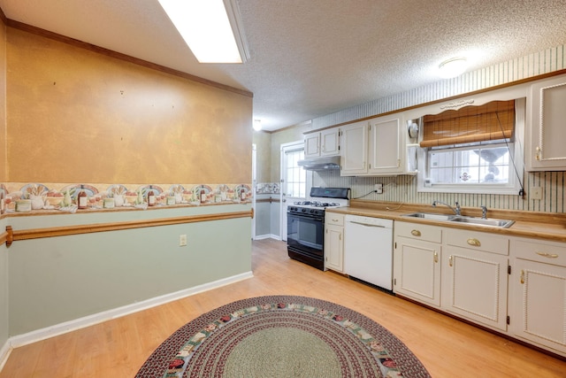 kitchen featuring light wood-type flooring, gas range, under cabinet range hood, a sink, and white dishwasher