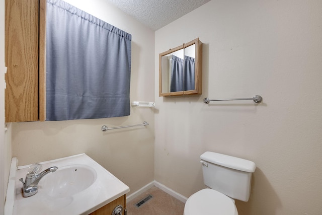 bathroom with vanity, toilet, baseboards, a textured ceiling, and visible vents