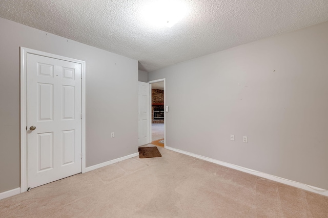 unfurnished bedroom with light colored carpet, baseboards, and a textured ceiling