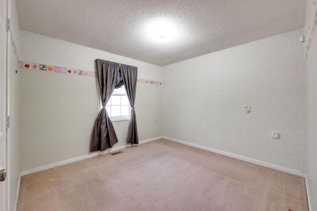spare room featuring baseboards, a textured ceiling, visible vents, and light colored carpet