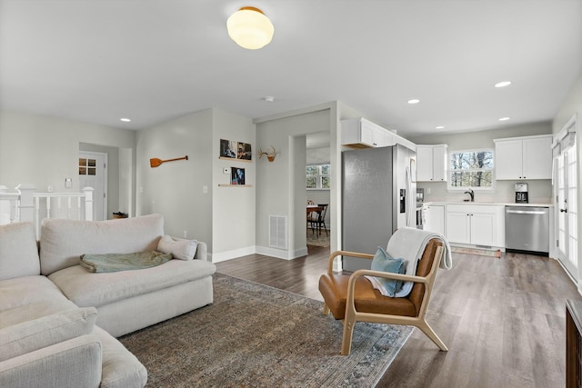 living room featuring baseboards, visible vents, recessed lighting, and wood finished floors