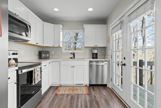 kitchen with light countertops, dark wood-style flooring, stainless steel appliances, a sink, and white cabinets