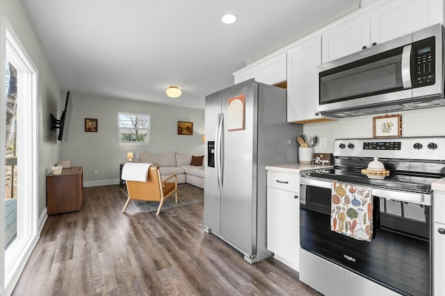 kitchen featuring open floor plan, light countertops, stainless steel appliances, dark wood-type flooring, and white cabinets