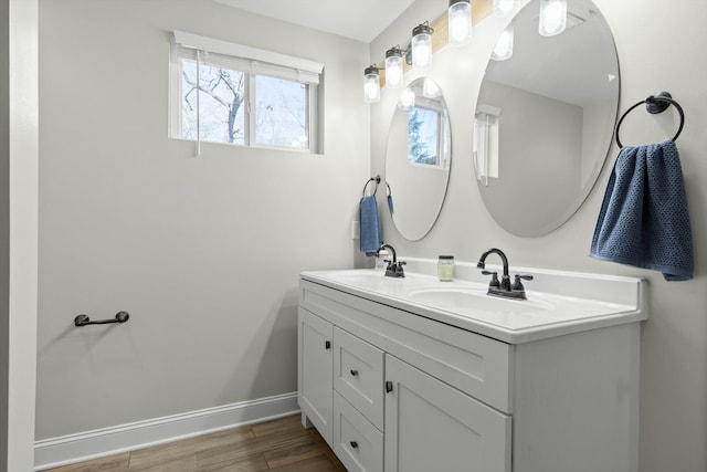 bathroom featuring double vanity, a sink, baseboards, and wood finished floors