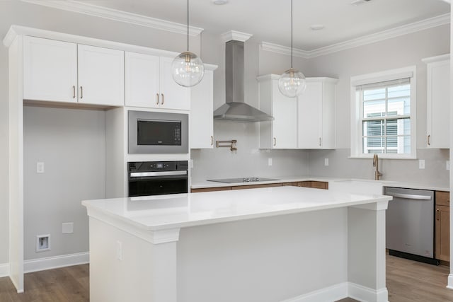 kitchen with white cabinets, wood finished floors, wall chimney exhaust hood, a kitchen island, and black appliances