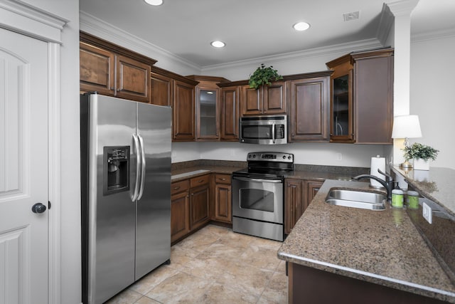 kitchen with ornamental molding, dark stone countertops, a sink, appliances with stainless steel finishes, and glass insert cabinets