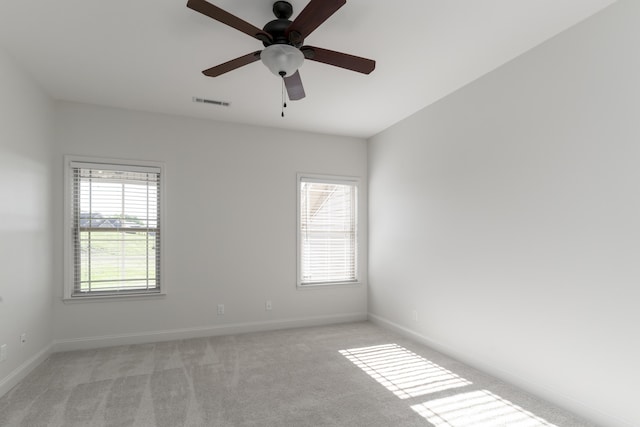 unfurnished room with ceiling fan, baseboards, light colored carpet, and visible vents