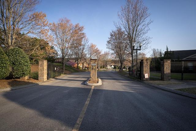 view of road with a gate, a gated entry, and curbs
