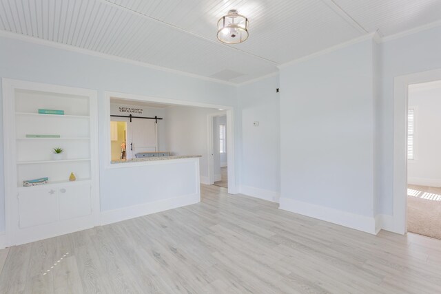 909 Stewart Ave, Chickamauga, GA 30707 - unfurnished living room featuring built in features, crown molding, a barn door, and light wood finished floors