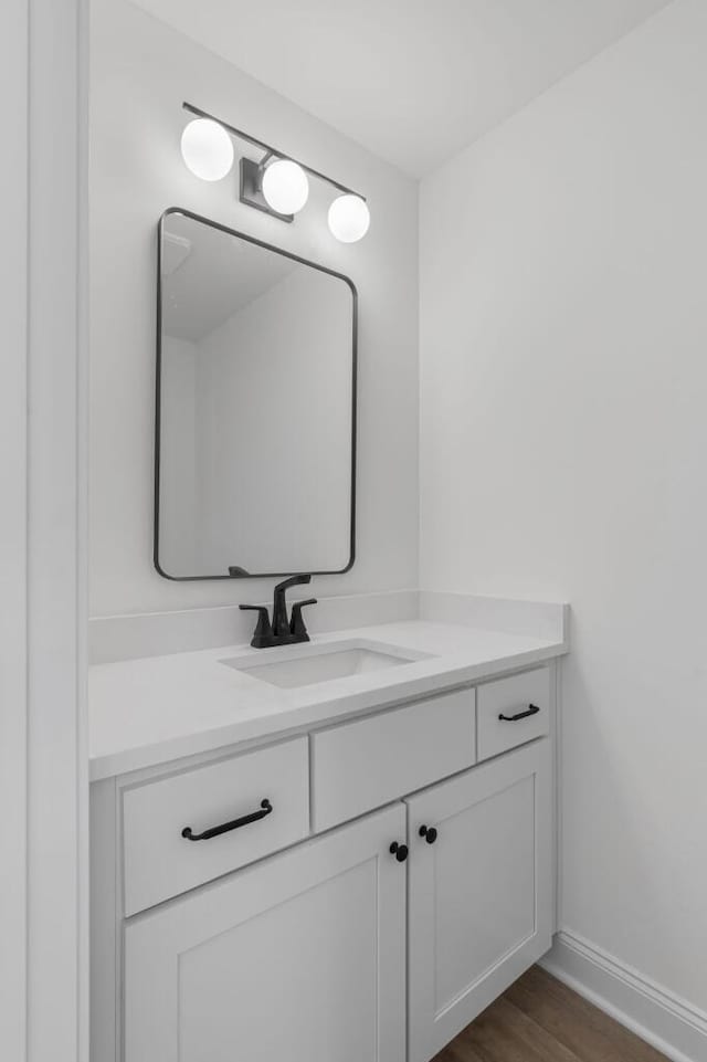 bathroom featuring baseboards, wood finished floors, and vanity