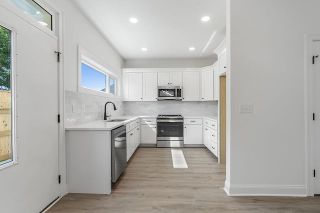 kitchen featuring decorative backsplash, light wood finished floors, a sink, and appliances with stainless steel finishes