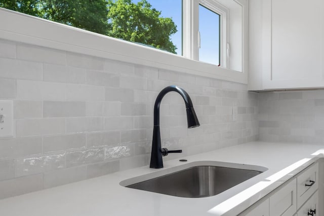 details featuring backsplash, white cabinets, a sink, and light countertops