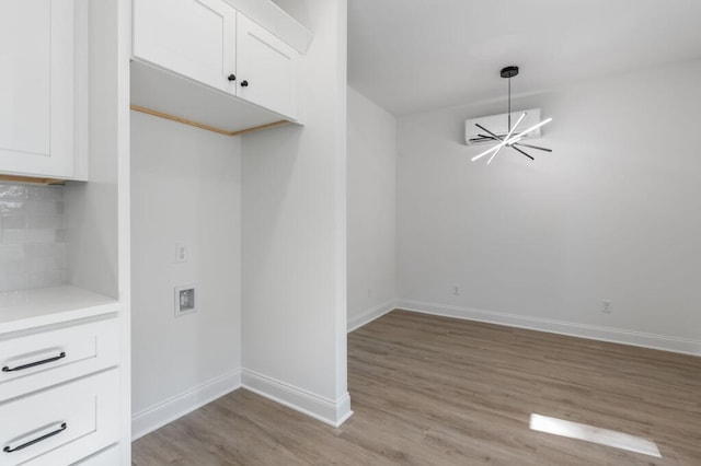 washroom featuring washer hookup, baseboards, laundry area, light wood-style floors, and an inviting chandelier
