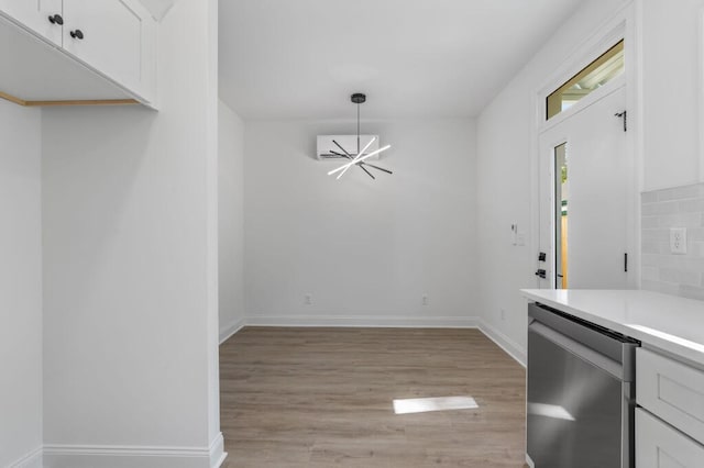 unfurnished dining area featuring baseboards, light wood-style flooring, and a notable chandelier