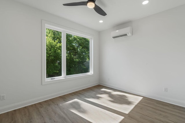 spare room with wood finished floors, an AC wall unit, and a wealth of natural light