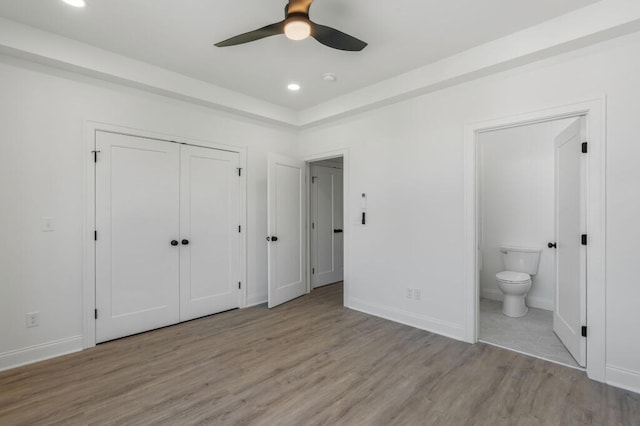 unfurnished bedroom featuring recessed lighting, baseboards, ensuite bathroom, and wood finished floors