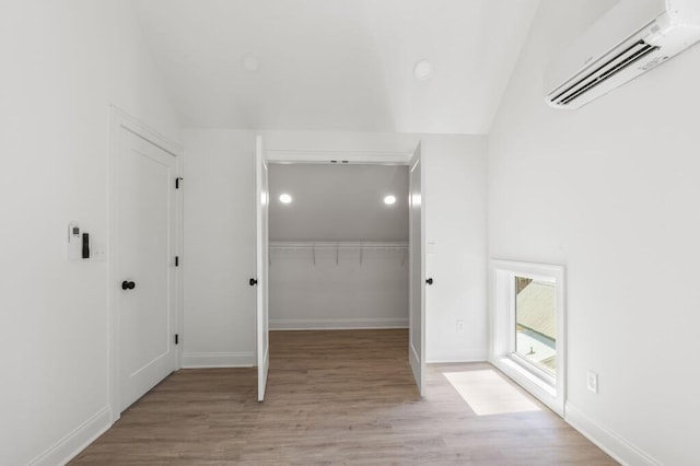 interior space featuring baseboards, light wood-style flooring, and an AC wall unit