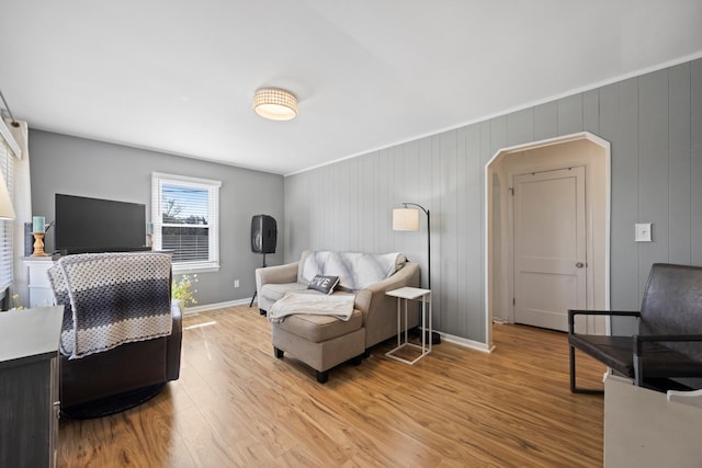 living room featuring baseboards, arched walkways, and light wood-style flooring