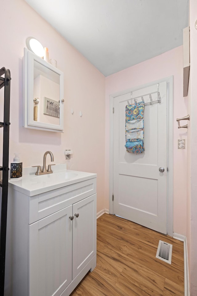 bathroom featuring baseboards, visible vents, vanity, and wood finished floors