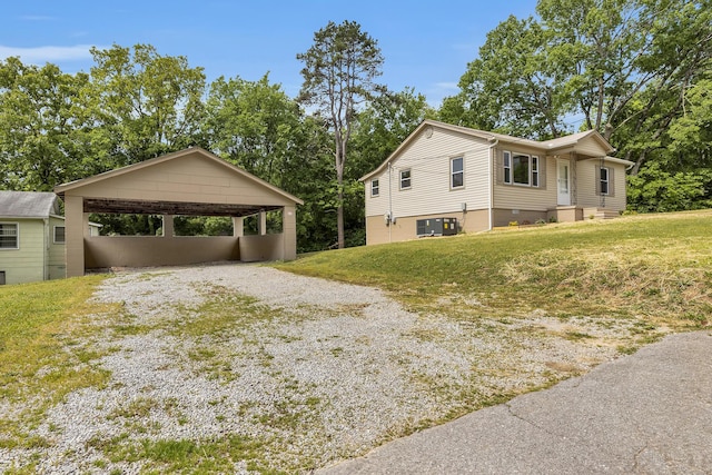 view of side of property featuring a lawn, gravel driveway, and a carport
