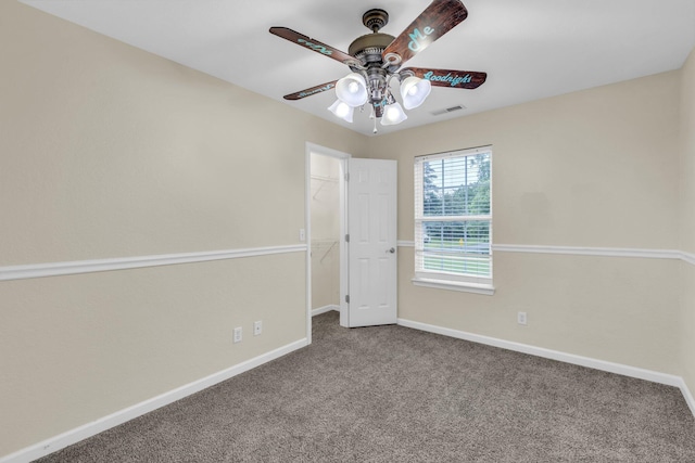 carpeted empty room with baseboards, a ceiling fan, and visible vents