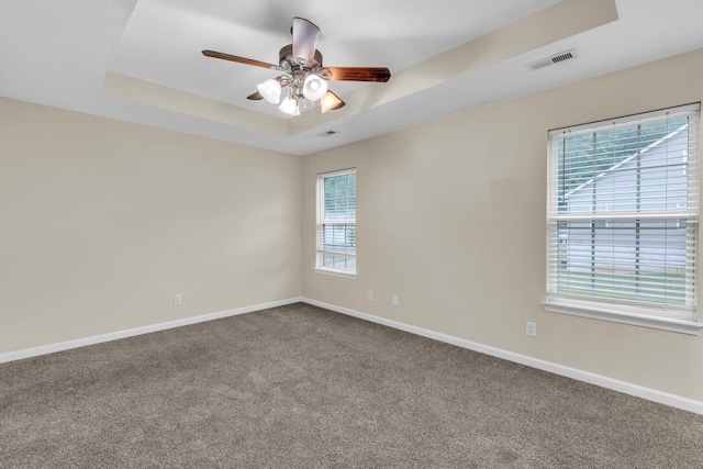 spare room with ceiling fan, a raised ceiling, carpet, baseboards, and visible vents