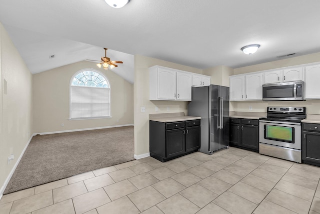 kitchen with light countertops, appliances with stainless steel finishes, white cabinets, and lofted ceiling