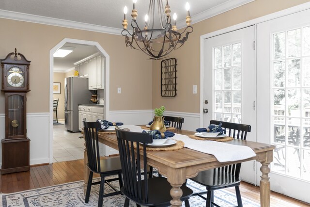 9215 Smokewood Trl, Chattanooga, TN 37421 - dining space with arched walkways, a chandelier, light wood finished floors, crown molding, and a wainscoted wall