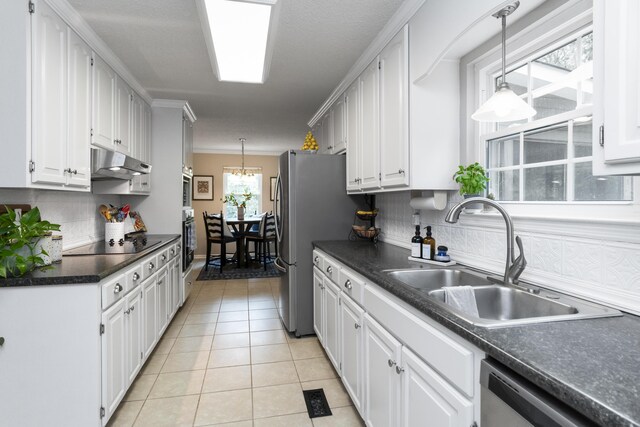 9215 Smokewood Trl, Chattanooga, TN 37421 - kitchen featuring appliances with stainless steel finishes, dark countertops, under cabinet range hood, light tile patterned flooring, and white cabinetry