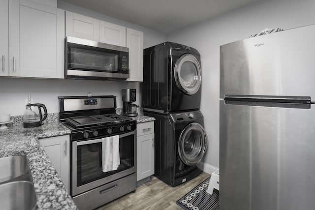9215 Smokewood Trl, Chattanooga, TN 37421 - kitchen with appliances with stainless steel finishes, stacked washer / drying machine, light stone countertops, white cabinets, and light wood-type flooring