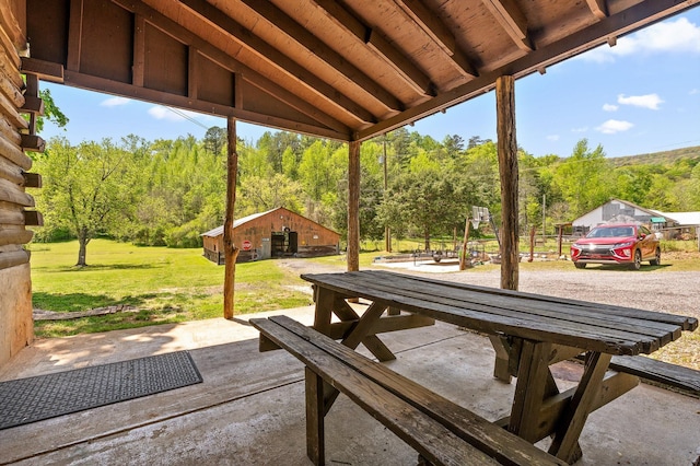 view of patio featuring an outdoor structure and a view of trees
