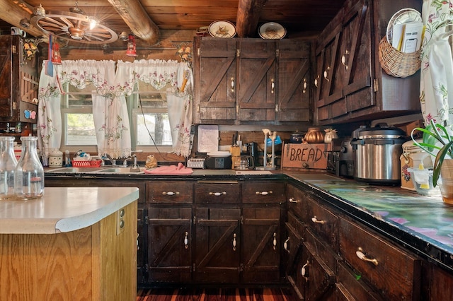kitchen featuring wooden ceiling, dark brown cabinets, beamed ceiling, and a sink