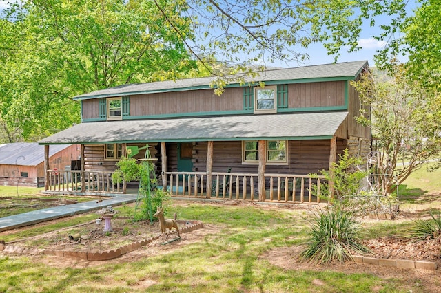 view of front facade with covered porch, a shingled roof, and log exterior