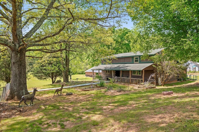 rear view of house featuring a yard, covered porch, and log exterior